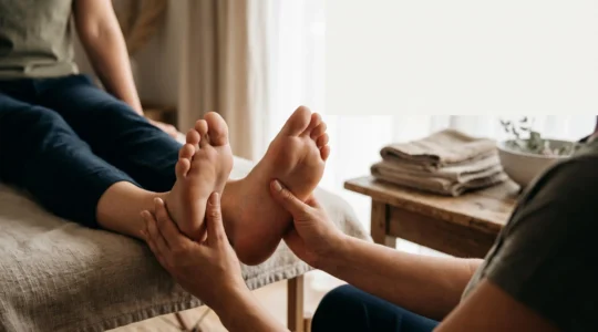 Mains d'un praticien effectuant une pression douce sur la voûte plantaire pour illustrer la régulation hormonale naturelle par réflexologie